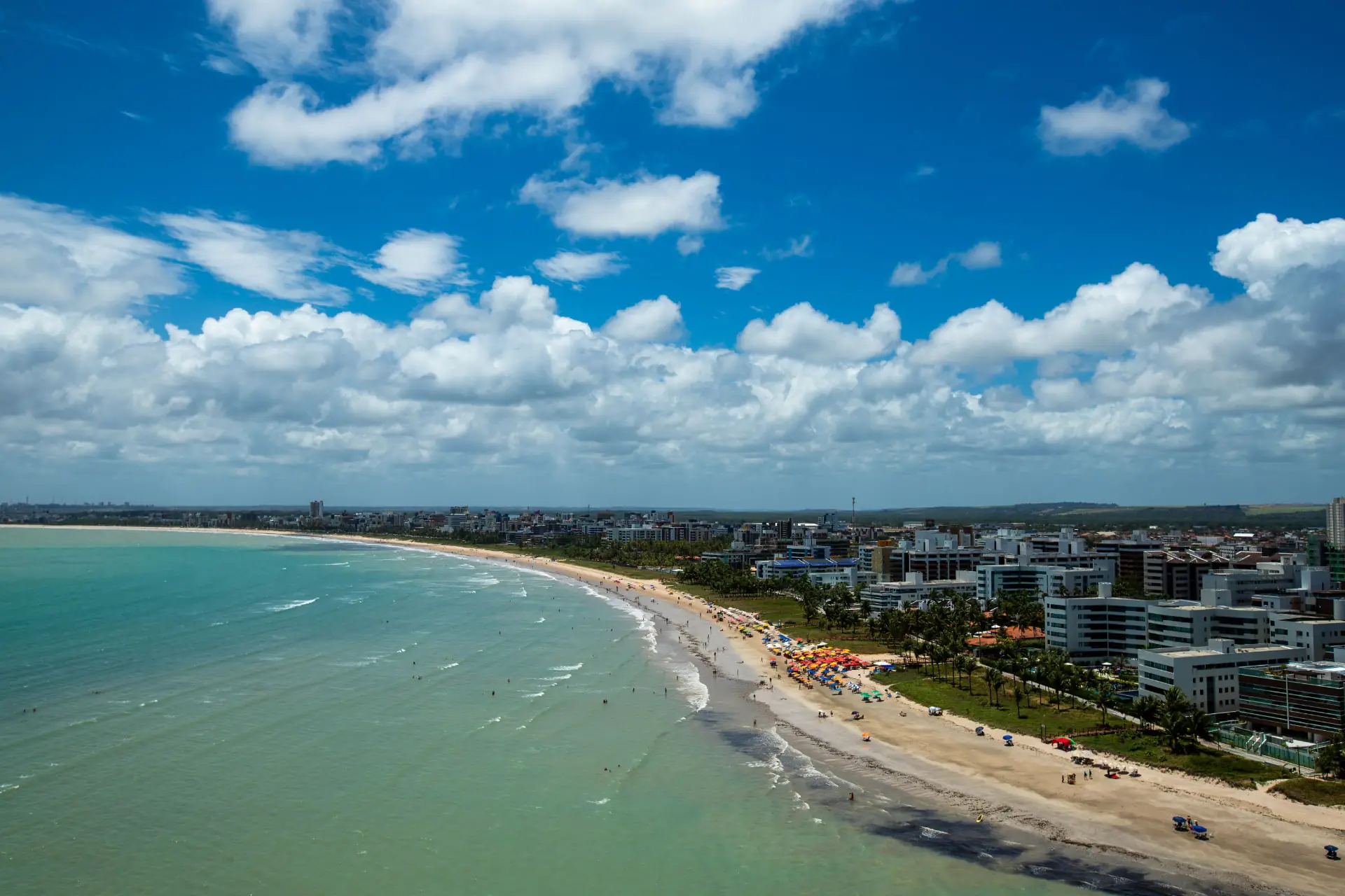 Vista elevada da orla de Cabo Branco, em João Pessoa, com o mar à esquerda e a cidade à direita
